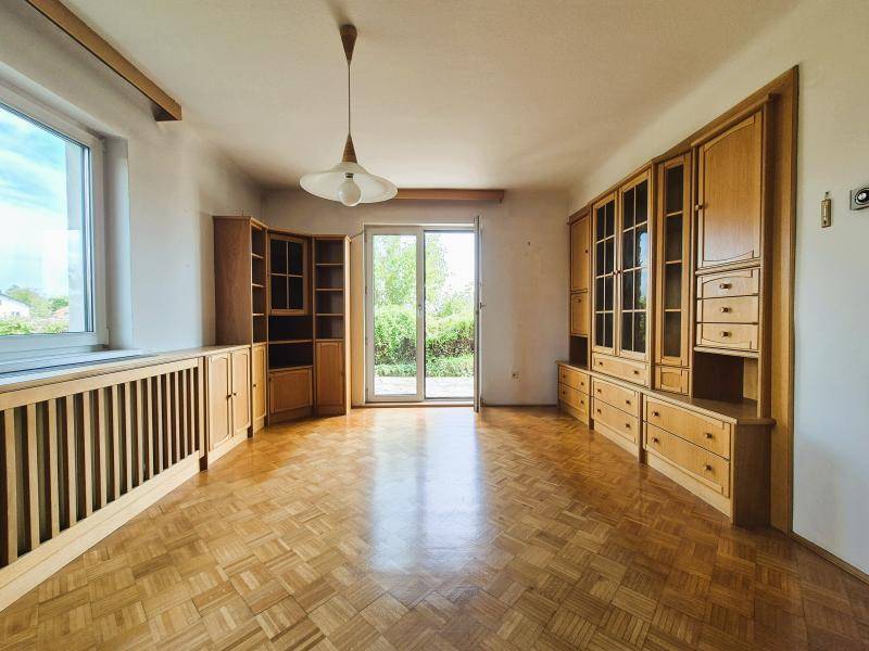 Helles Wohnzimmer mit Parkettboden, großen Fenstern und Zugang zum Gartenbereich.