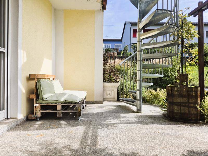 Gemütliche Terrasse mit Palettenmöbeln und einer Wendeltreppe, die zum oberen Balkon führt.