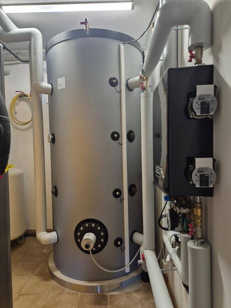 Technikraum mit großem Warmwasserspeicher und zahlreichen Rohrleitungen.