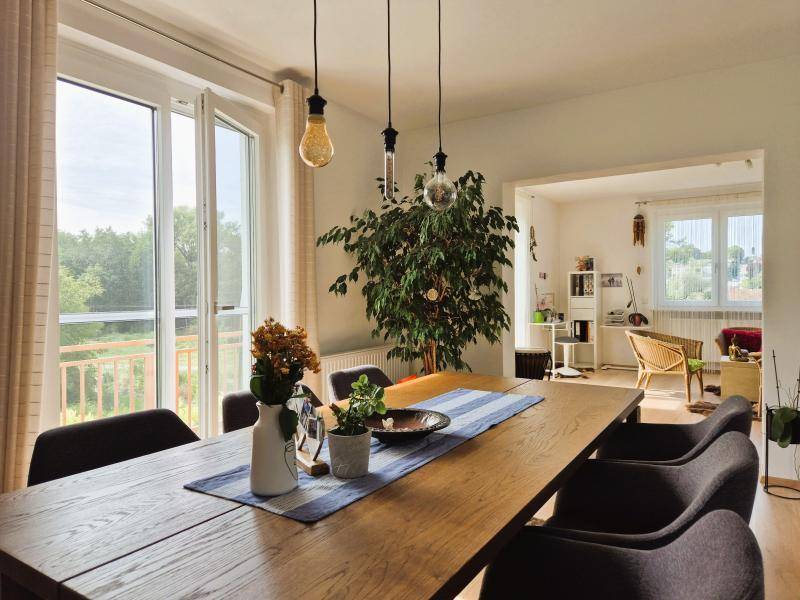 Heller Essbereich mit Holztisch, Pflanzen und Zugang zum Balkon durch große Fenstertüren.