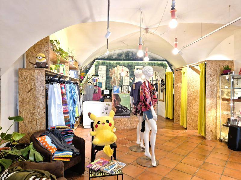 Bekleidungsgeschäft mit gewölbter Decke, Terrakottafliesen und Schaufensterpuppen, die Kleidung präsentieren.