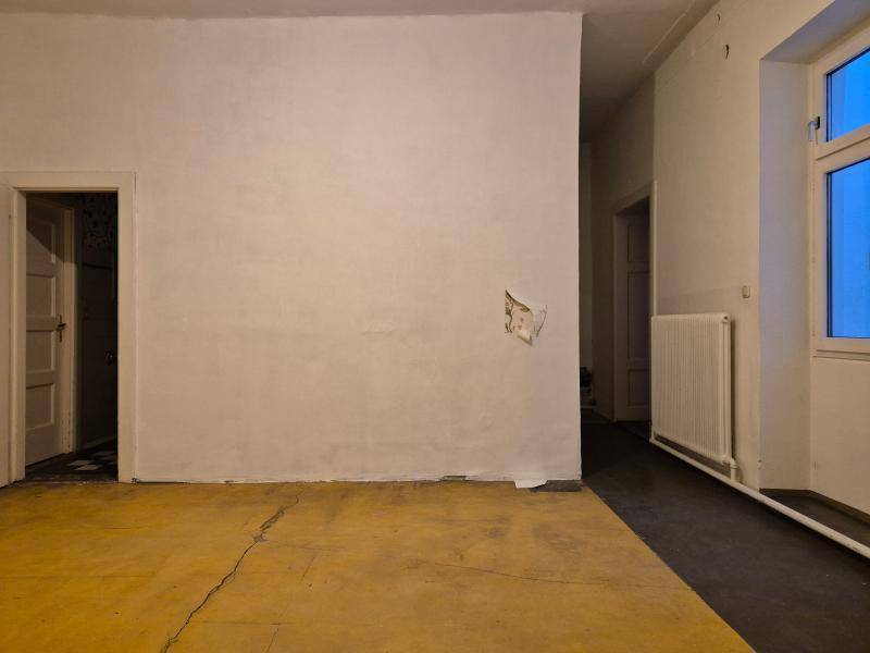 Raum in Renovierung mit gelbem Unterboden und einer weißen Wand, die auf zukünftige Gestaltung wartet.