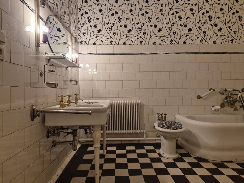 Traditionelles Badezimmer mit kariertem Fliesenboden, einer Badewanne und einem Waschbecken im Vintage-Stil.