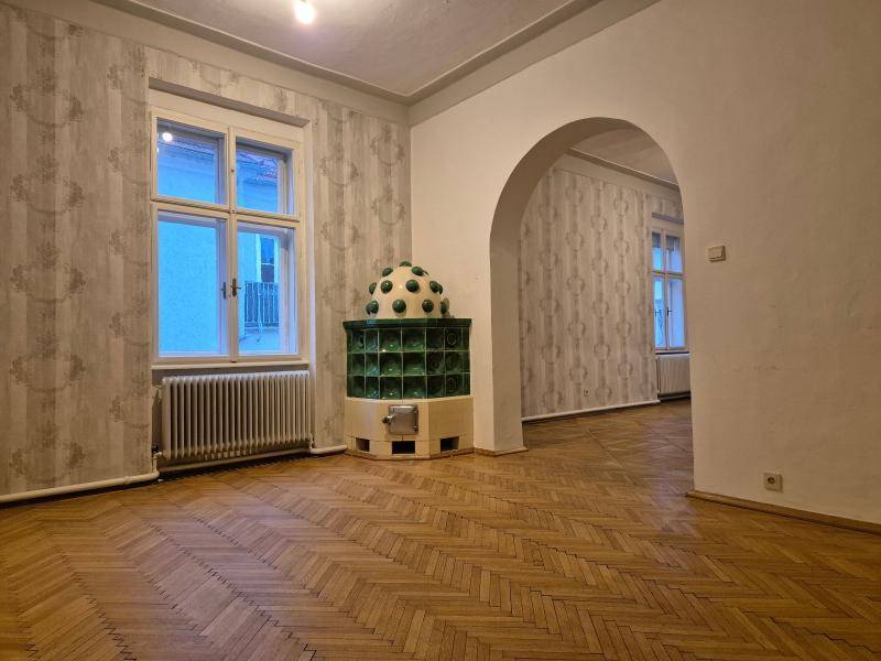 Geräumiges Zimmer mit einem auffälligen grünen Kachelofen und einem eleganten Bogen, der zu einem weiteren Bereich führt.