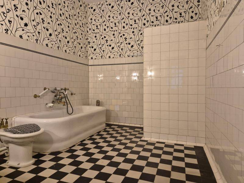 Geräumiges Badezimmer mit schwarz-weißem Fliesenboden und einer Badewanne, ergänzt durch eine Duschzone.