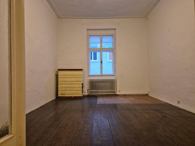 Kleineres Zimmer mit dunklem Holzboden und einem Fenster, das den Raum erhellt, ideal als Schlafzimmer.