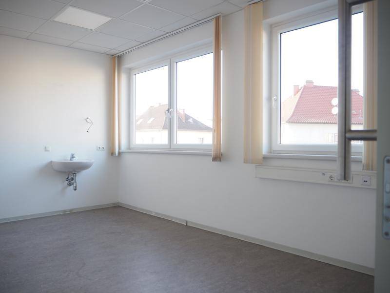 Heller Raum mit Waschbecken, zwei Fenstern und Blick auf die umliegenden Dächer.
