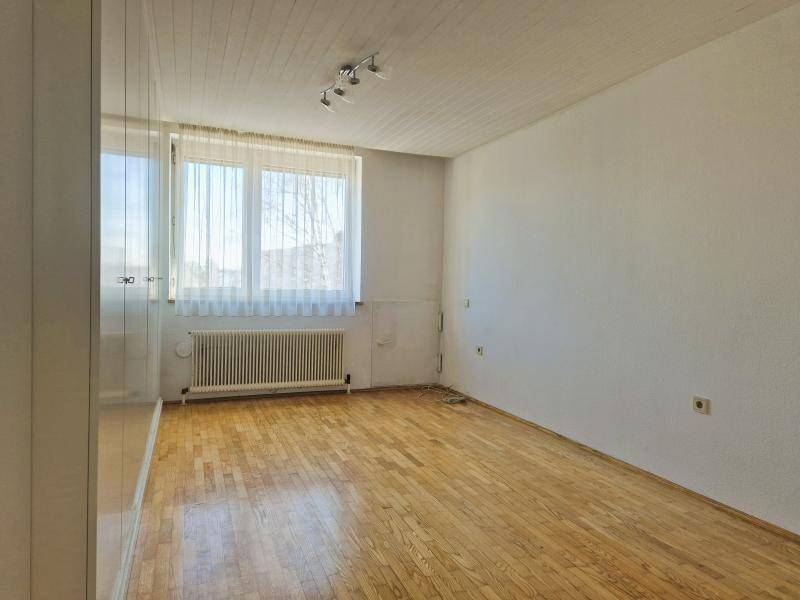 Helles Schlafzimmer mit Parkettboden, großem Fenster und ausreichend Platz.