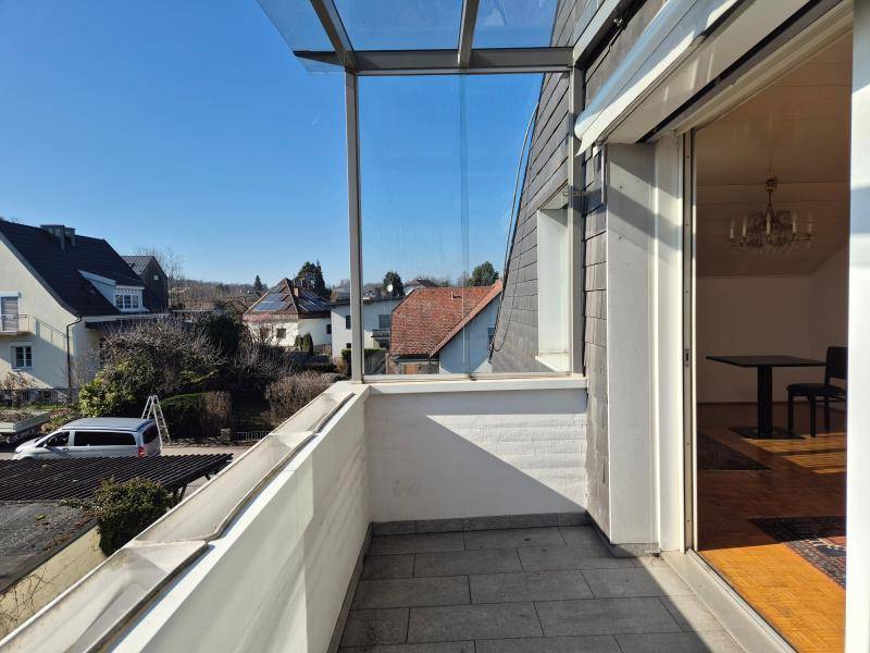 Balkon mit Fliesenboden und Blick auf die umliegenden Häuser und Landschaft.
