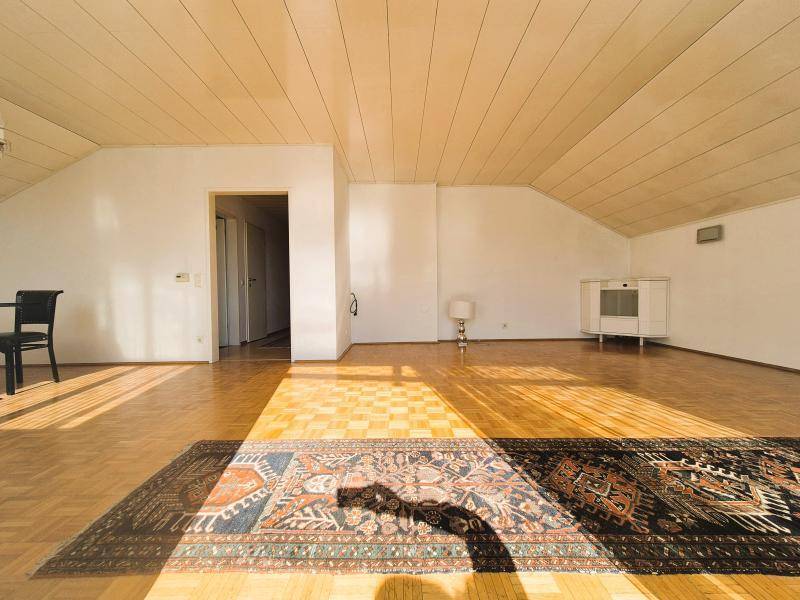Geräumiges, helles Zimmer mit Parkettboden und Dachschräge, ideal als Wohnbereich.