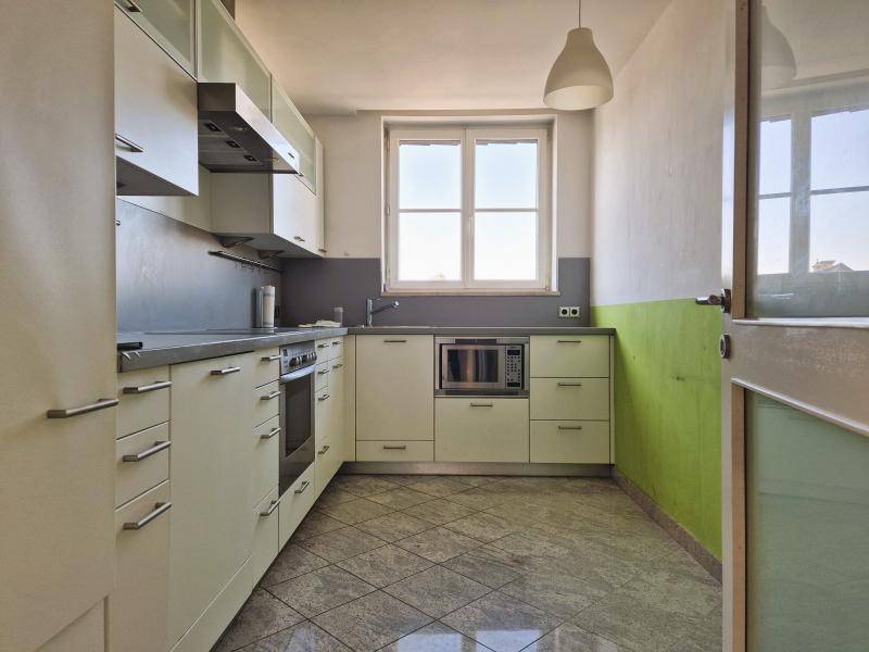 Funktionale Küche mit hellen Einbauschränken, Fenster und gefliestem Boden.
