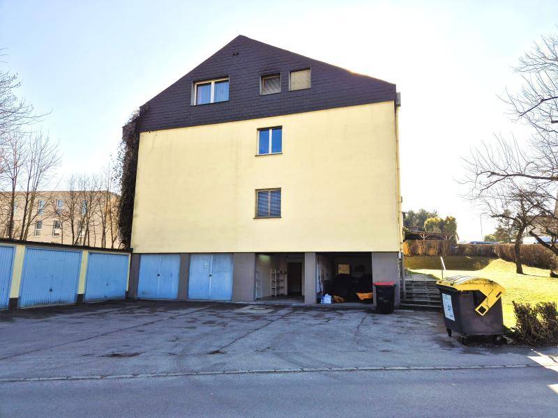 Rückseite des Gebäudes mit Garagenzugang und Parkplätzen im Freien.