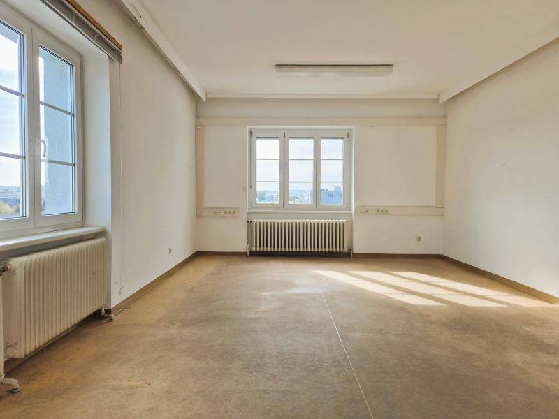 Geräumiger Büroraum mit mehreren Fenstern und Heizkörpern, der viel natürliches Licht erhält.