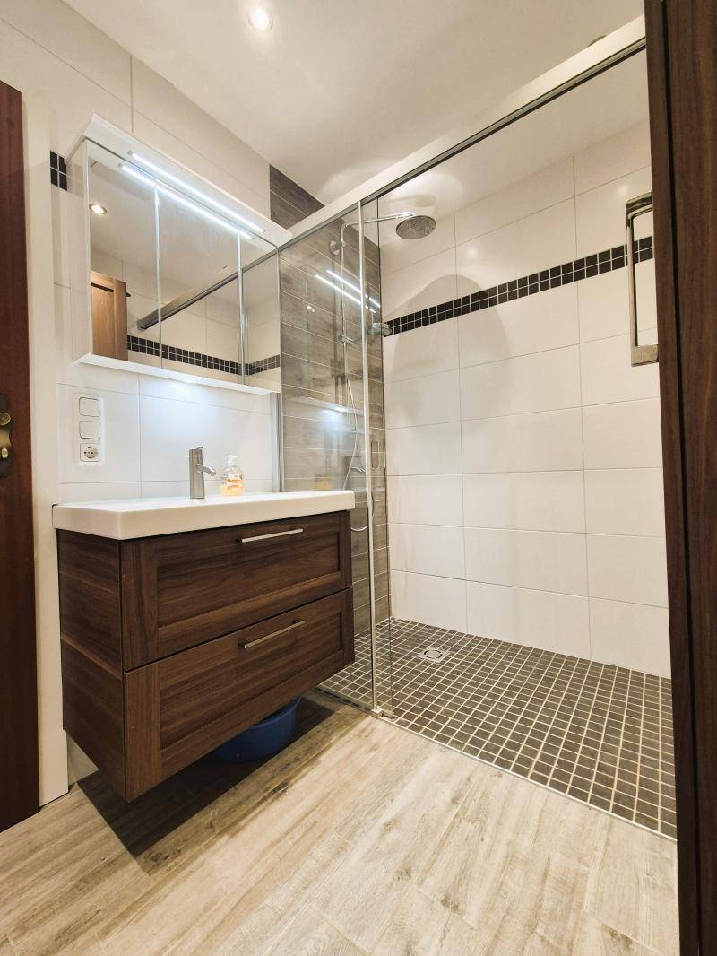 Modernes Badezimmer mit begehbarer Dusche, schwebendem Waschtisch und Spiegelschrank.