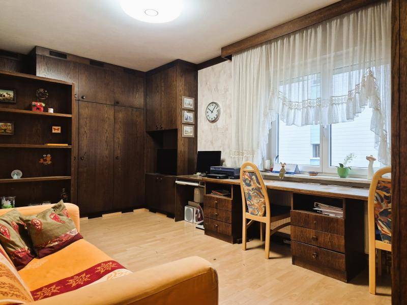 Arbeitszimmer mit großem Schreibtisch, dunklen Holzmöbeln und Blick ins Grüne.