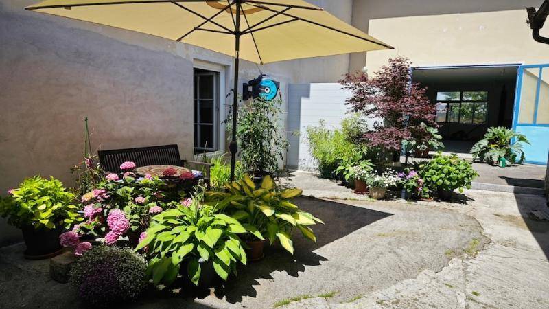 Kleiner Innenhofgarten mit verschiedenen Pflanzen, Sitzbank und Sonnenschirm.