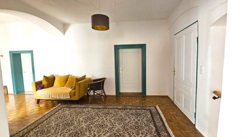 Heller Wohnbereich mit gelbem Sofa, Parkettboden und Türen mit grünen Rahmen.