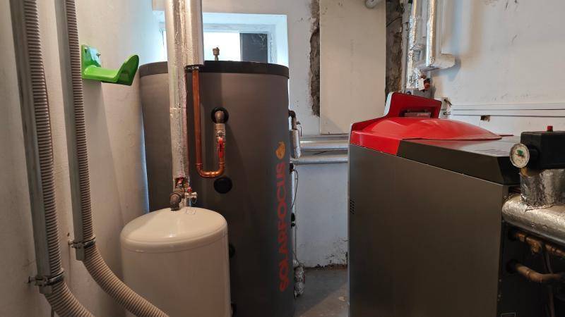Heizungsraum mit modernen Heizkesseln, Warmwasserspeicher und sichtbaren Rohren.