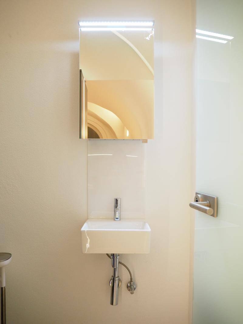 Helles Badezimmer mit modernem Waschbecken, Spiegelschrank und minimalistischem Design.