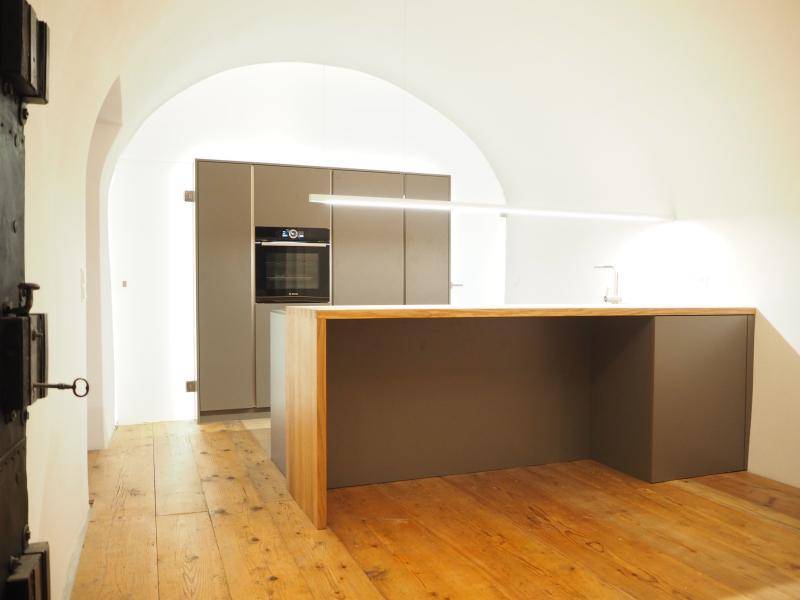 Moderne Küche mit Kücheninsel, integriertem Backofen und Gewölbedecke.