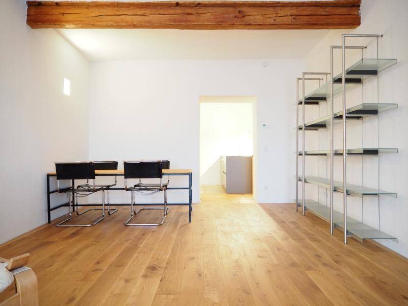 Geräumiges Wohnzimmer mit Holzbalken, Holzboden und modernem Regal, offen gestaltet.