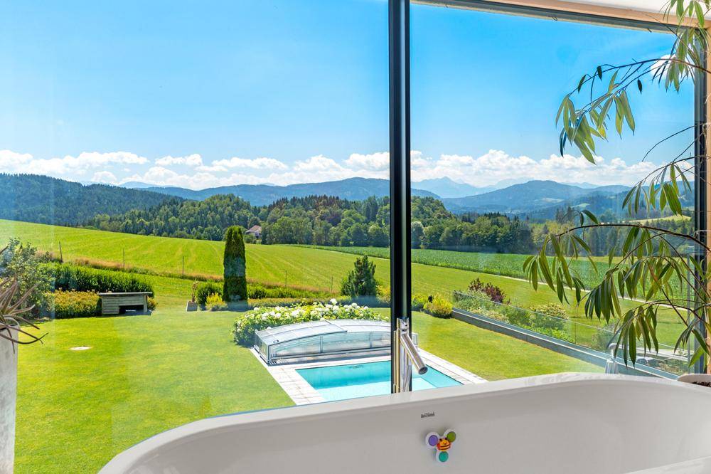 Luxuriöses Badezimmer mit freistehender Badewanne und Panoramafenstern, die einen atemberaubenden Ausblick bieten.