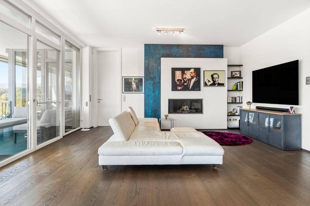 Gemütliches Wohnzimmer mit weißem Sofa, Holzboden und modernem Kamin als Blickfang.