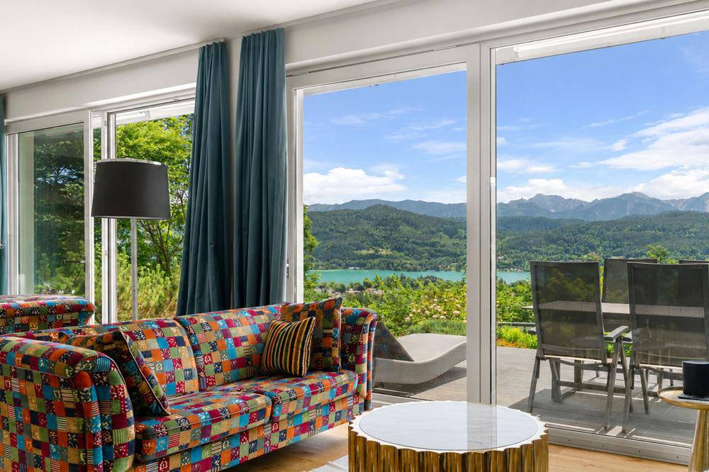 Gemütliches Wohnzimmer mit Patchwork-Sofa und direktem Zugang zur Terrasse mit Seeblick.