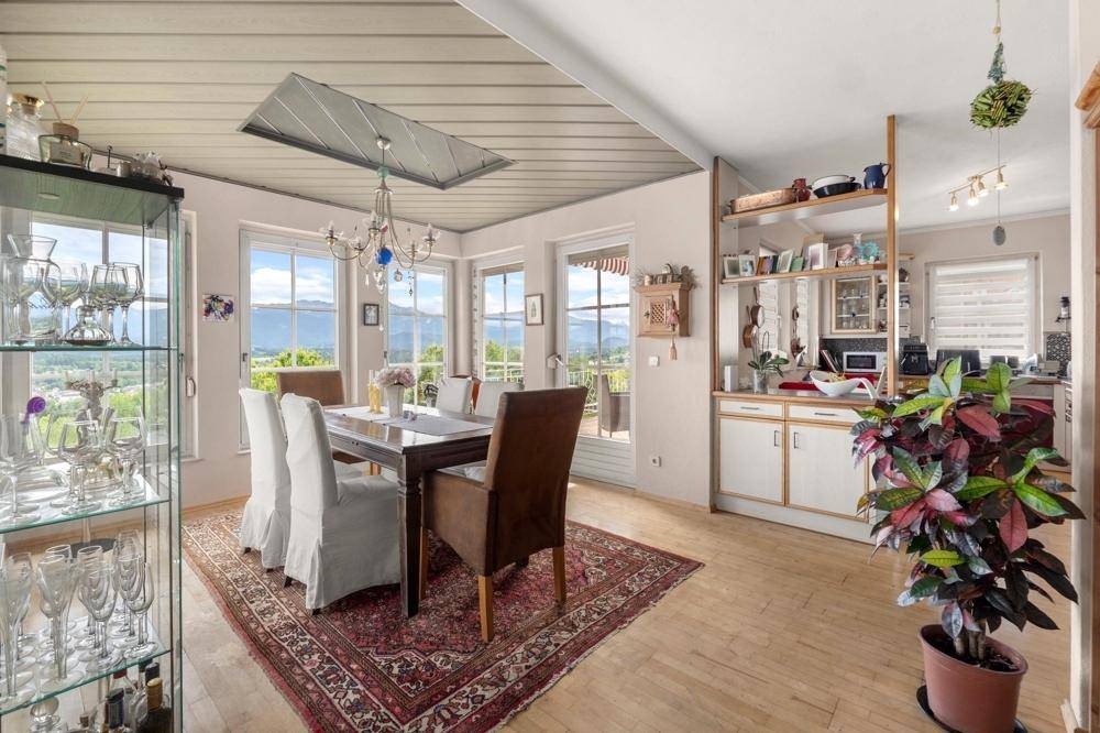 Eleganter Essbereich mit Holztisch, Kronleuchter und Blick auf die umliegende Landschaft.
