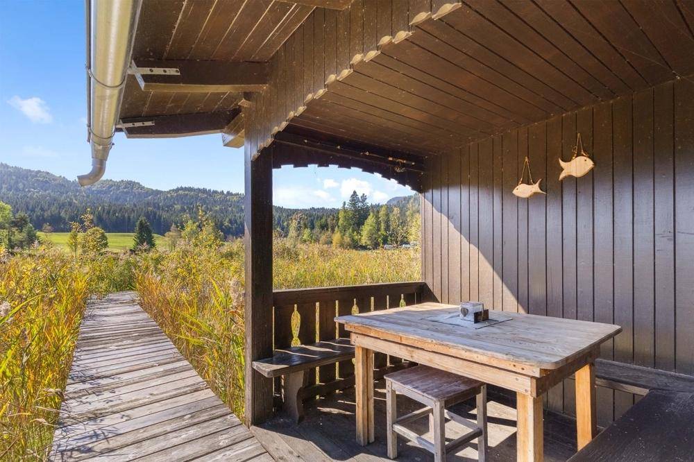 Überdachter Sitzbereich im Freien mit Holztisch und Bänken, bietet einen weiten Blick auf die Natur.