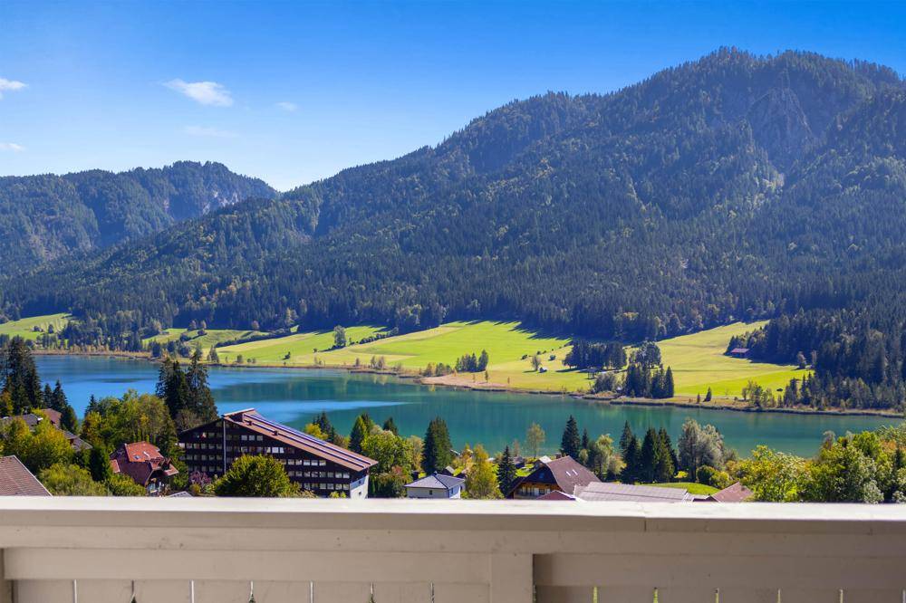 Atemberaubender Panoramablick vom Balkon auf den See, grüne Landschaft und die umliegenden Berge.