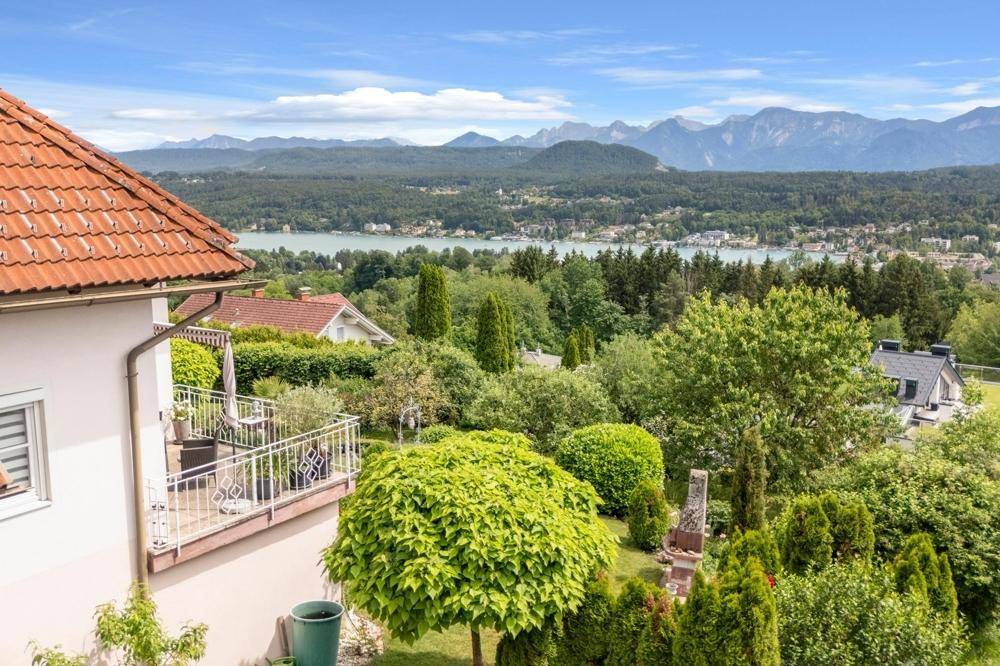 Weitläufiger Blick über den See und die Berge, umgeben von üppiger grüner Natur.