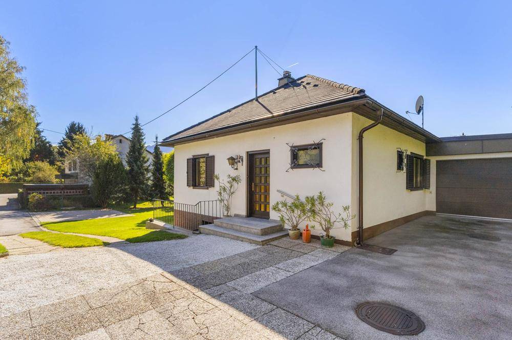 Vorderansicht des Hauses mit Eingangsbereich, Garage und gepflasterter Zufahrt.