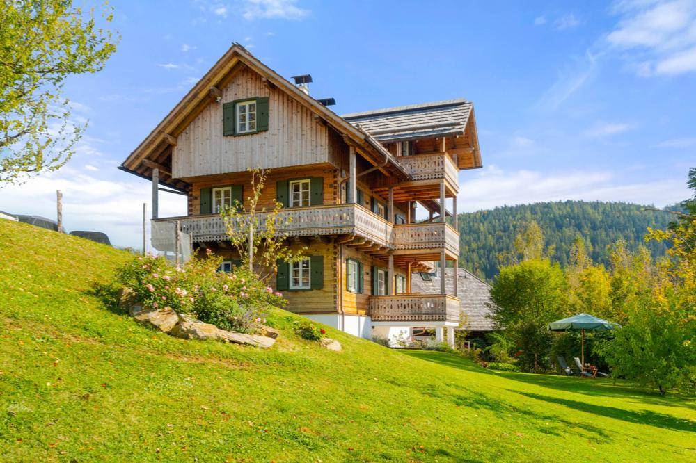 Charmantes Holzhaus mit mehreren Balkonen und einem gepflegten Gartenbereich.
