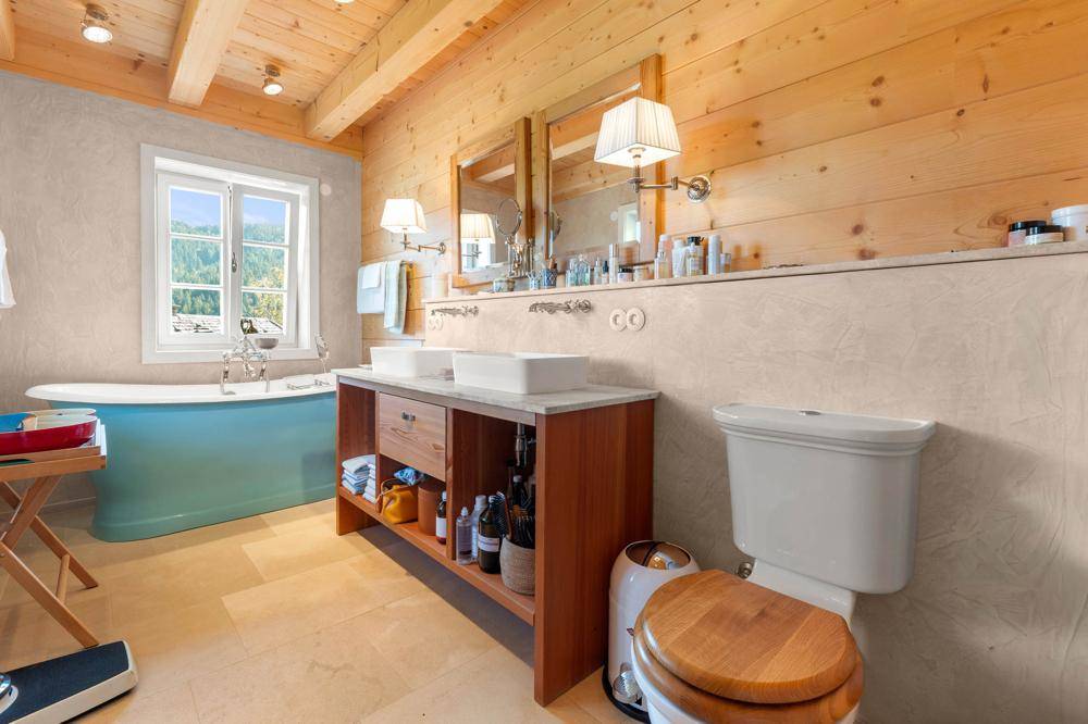 Geräumiges Badezimmer mit Doppelwaschbecken, Badewanne und Holzwänden.