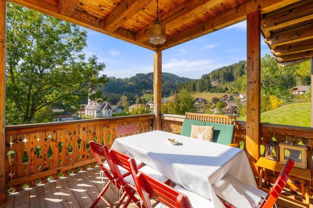 Geräumiger Holzbalkon mit Esstisch und Stühlen, bietet einen weiten Blick auf die Landschaft.