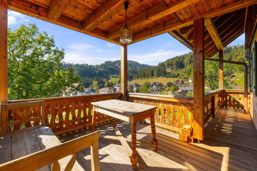 Großer Holzbalkon mit traditionellem Geländer und Panoramablick auf die umliegende Landschaft.