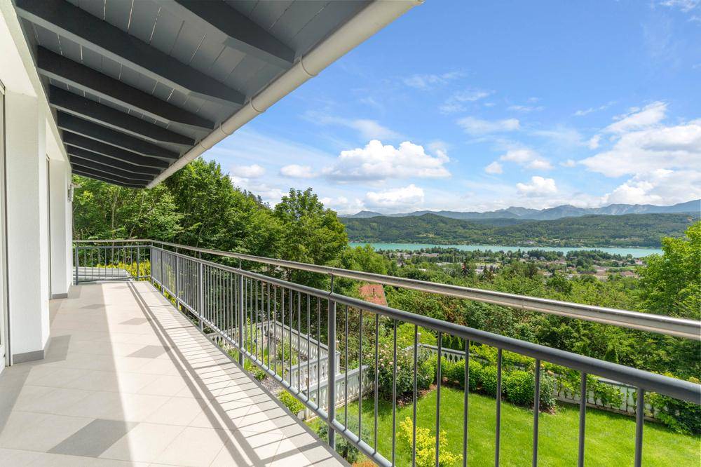 Langer Balkon mit Metallgeländer und atemberaubendem Panoramablick auf den See und die Berge.