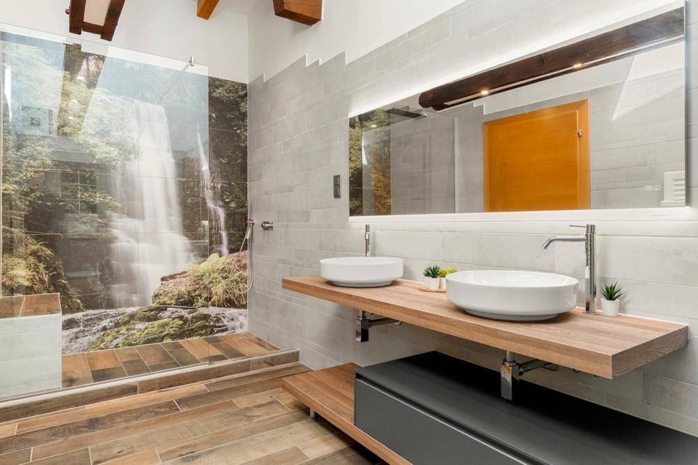 Modernes Badezimmer mit Doppelwaschbecken, großer Dusche und Naturmotiv an der Wand.