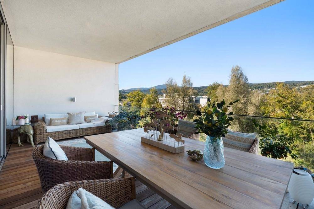 Große überdachte Terrasse mit Lounge-Möbeln und Esstisch, bietet weite Aussicht auf die Umgebung.
