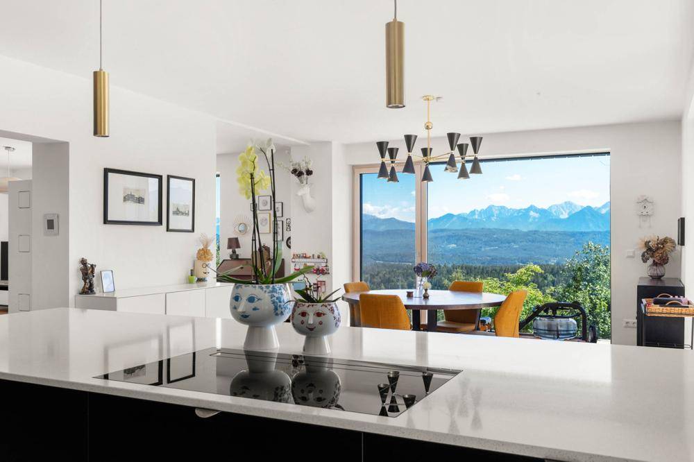 Moderne Küche mit Kücheninsel, Induktionskochfeld und offenem Blick auf den Essbereich und die Berge.