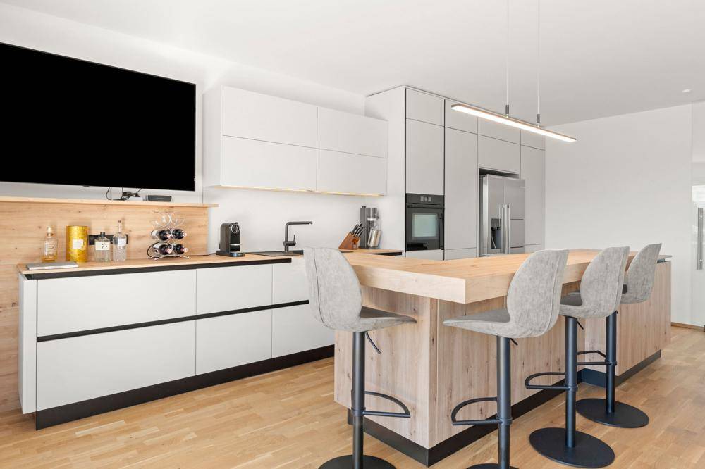 Moderne Einbauküche mit Kücheninsel, integrierten Geräten und Holzarbeitsplatten.
