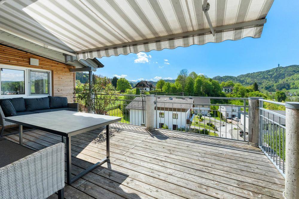 Sonnige Terrasse mit Markise, Sitzgelegenheiten und Panoramablick über die Landschaft.