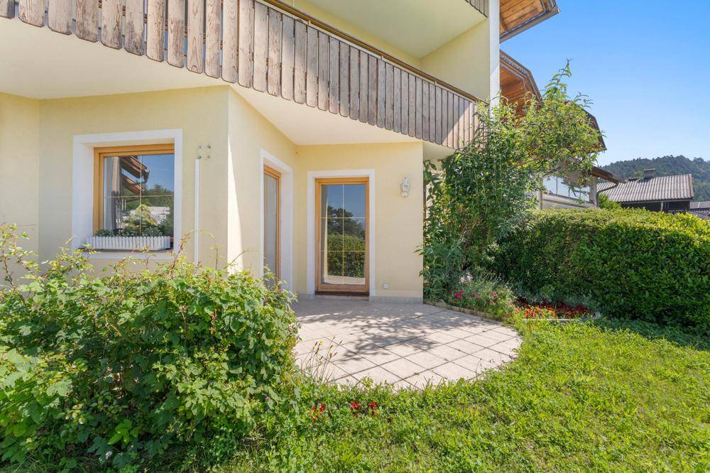 Außenbereich des Hauses mit einer kleinen gepflasterten Terrasse und umgebendem Garten.