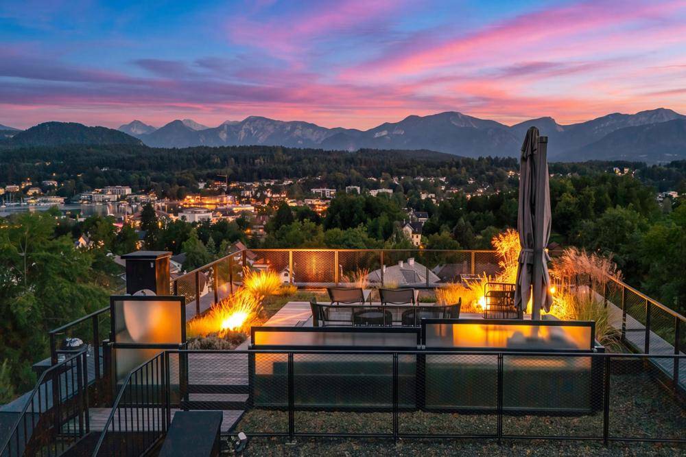 Stimmungsvolle Dachterrasse bei Sonnenuntergang mit Beleuchtung und spektakulärem Blick auf See und Berge.