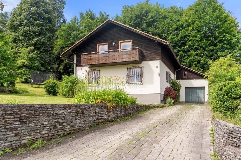 Einfamilienhaus mit Garage, Auffahrt und großem Garten in ländlicher Umgebung.