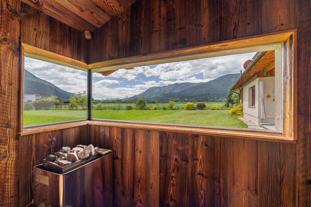 Moderne Sauna mit Holzverkleidung und Panoramafenster mit Bergblick.