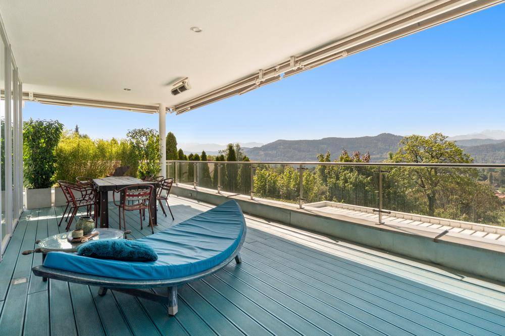 Geräumige überdachte Terrasse mit blauer Holzterrasse, Essbereich und atemberaubendem Bergblick.