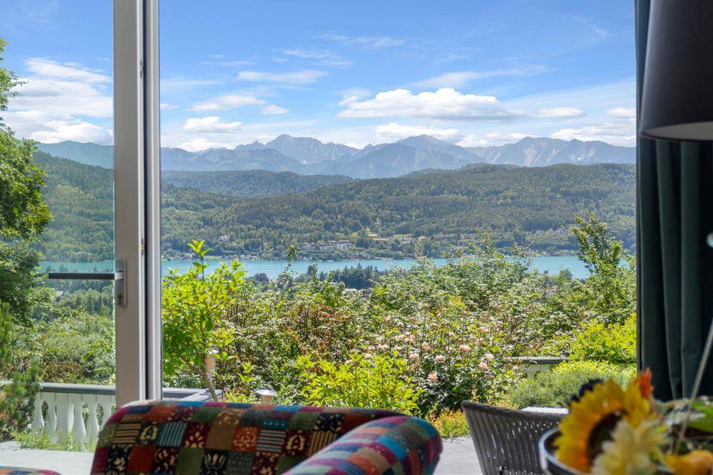 Heller Wohnbereich mit weitem Blick auf den See und die Berge durch große Panoramafenster.