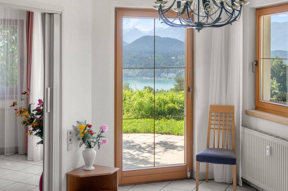 Nahaufnahme eines Fensters mit Blick auf den See und die umliegende grüne Landschaft.